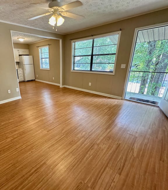 an empty living room with wood floors and a ceiling fan