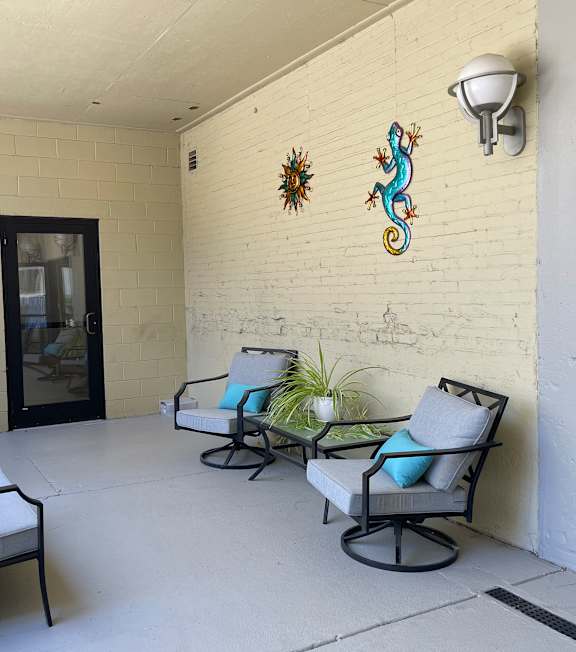 a patio with three chairs and a table and a door with a glass door