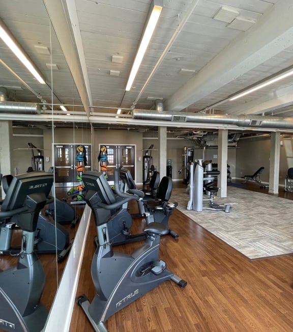 a gym with cardio machines and weights on a wooden floor