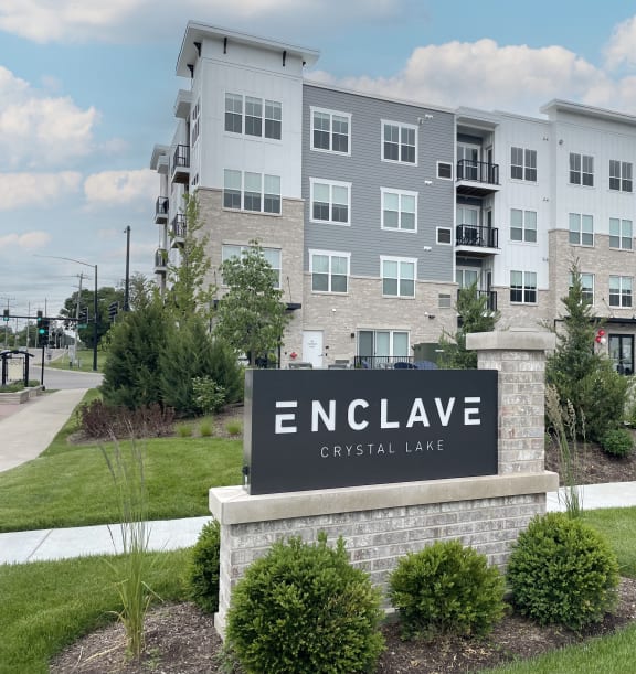 an exterior view of an enclave apartment building with a sign at Enclave Crystal Lake Townhomes and Apartments, Crystal Lake, 60014