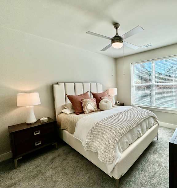 A bedroom with a large bed, a ceiling fan, and a nightstand with a lamp at The Collective Upper Westside Apartments, Atlanta, GA, 30318