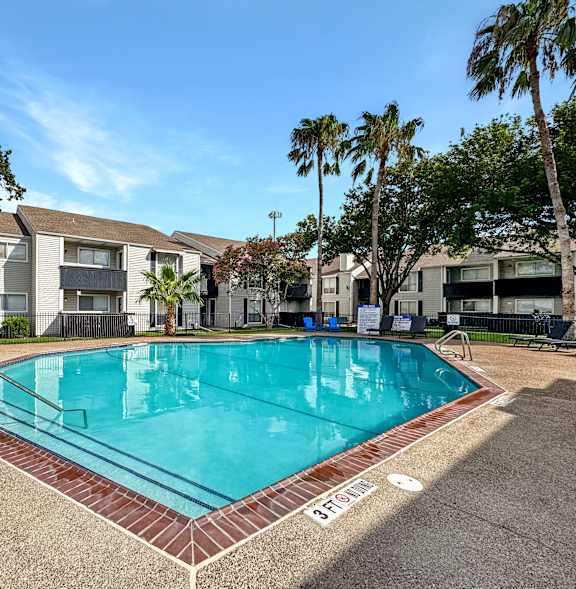 A swimming pool surrounded by palm trees and apartment buildings.