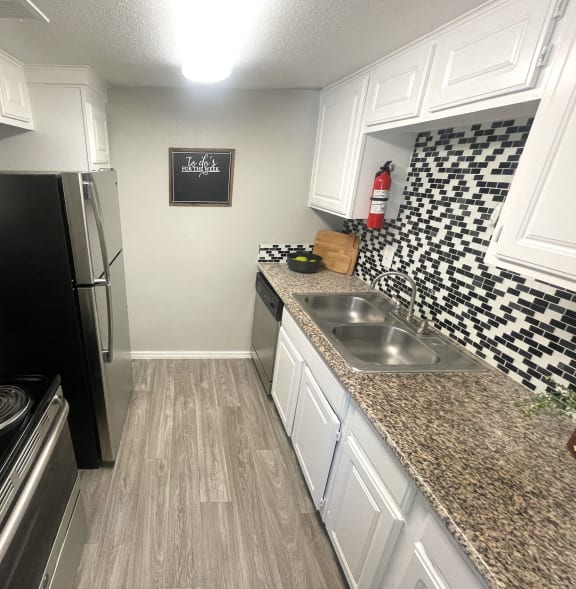 a kitchen with white cabinets and granite counter tops and a black refrigerator