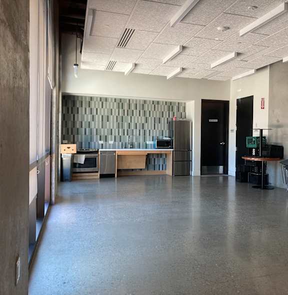 A room with a grey floor and a grey wall with a black door.