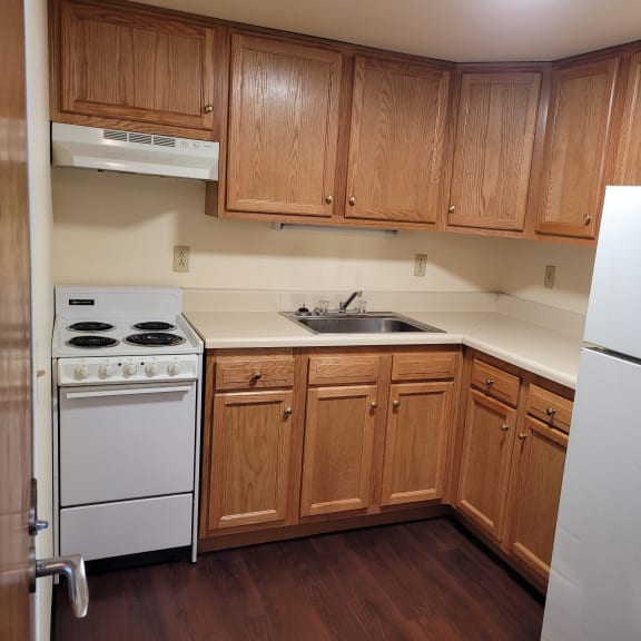 an empty kitchen with white appliances and wooden cabinets