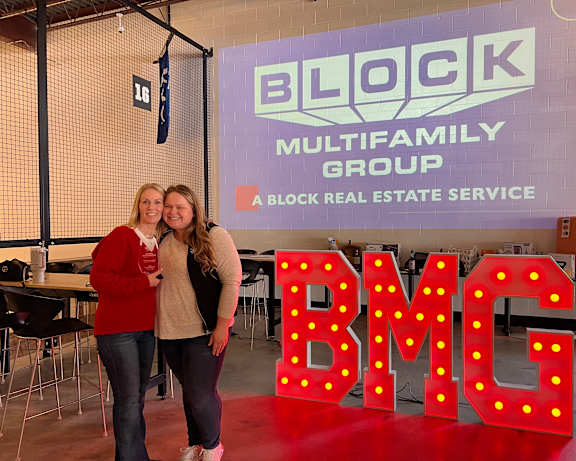 a group of people standing in front of a blokk real estate services logo