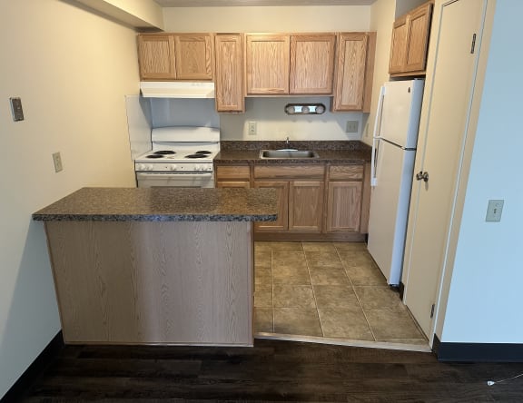 an empty kitchen with wooden cabinets and a white refrigerator