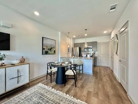 A modern kitchen with a dining table set for four.at Allier Gulf Shores, Gulf Shores, AL 36542