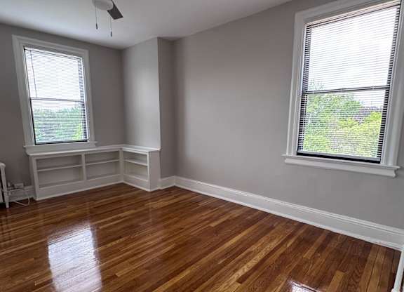 A room with a ceiling fan and wooden floors.