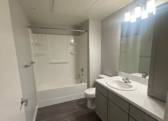 A bathroom with a toilet, sink, and mirror.