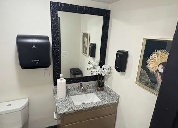 A bathroom with a toilet, sink, mirror, and a painting on the wall at Waverly Manor Townhomes, Georgia