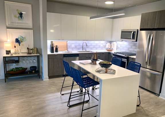 A kitchen with a white island and blue chairs. at Residences at Addison Clark, Chicago, IL, 60613
