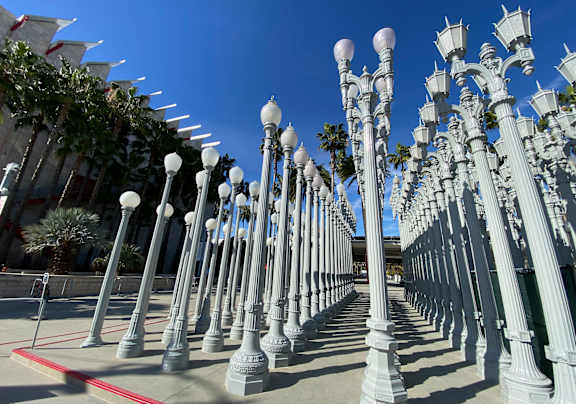 A row of white street lamps are lined up on a sidewalk.