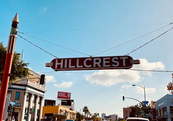 A street sign that says Hillcrest is hanging over a busy street.