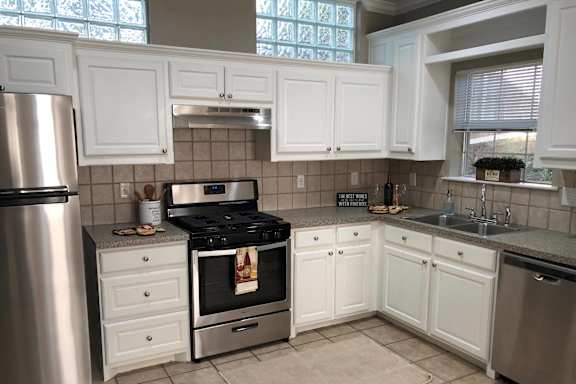 A kitchen with white cabinets and a stainless steel refrigerator.