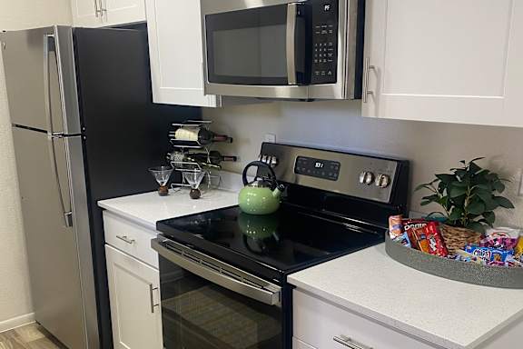 A kitchen with a refrigerator, microwave, and oven.