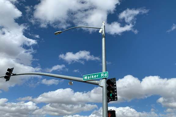 A street sign for Walker Rd is shown against a blue sky with clouds.