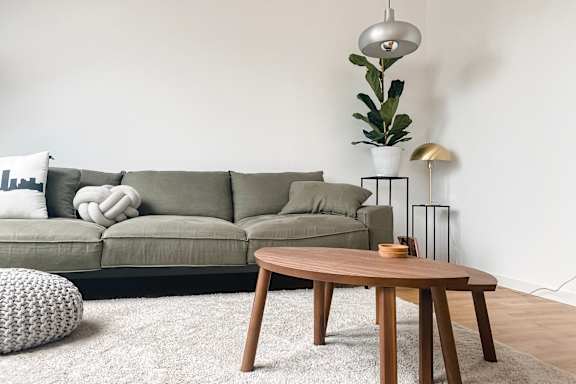 A modern living room with a grey sofa and a wooden wall.