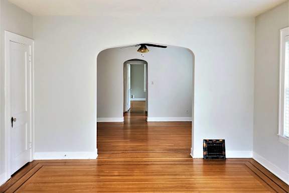 an empty room with a hard wood floor and an arched doorway