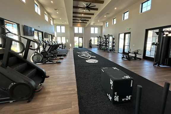 A gym with a variety of equipment including treadmills, weights, and exercise machines. at Stella Luxury Apartment Homes in San Tan Valley, AZ