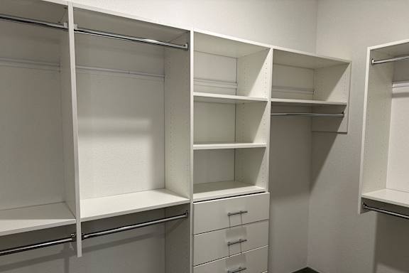 a walk in closet with shelves and drawers and