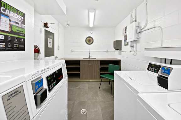 A clean, white-walled industrial kitchen with a washing machine and a microwave.