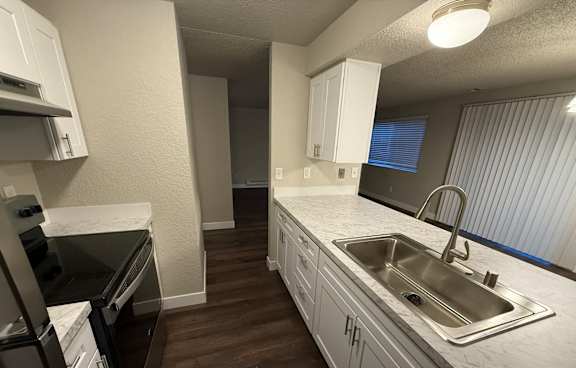 A kitchen with a stainless steel sink and refrigerator.