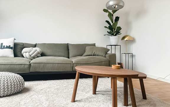 A living room with a grey couch, a wooden table, and a white pillow.