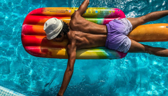 a man laying on a raft in a swimming pool at Telka Apartments, Silverdale