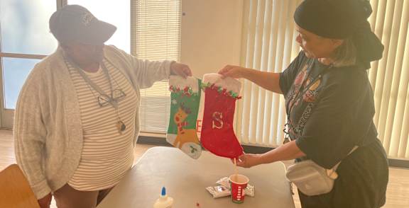 A woman is handing a red bag with a cartoon character to another woman.