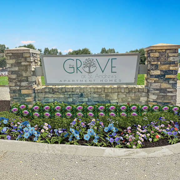 A sign for Grove at Andrews Apartment Homes is surrounded by flowers.