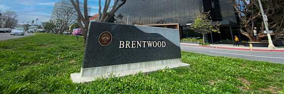 A modern glass building with a sign that reads "Brentwood" in front of it.