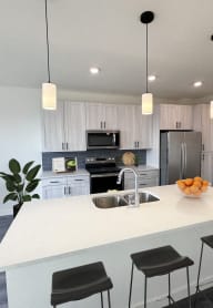 an open kitchen with a white counter top and a sink