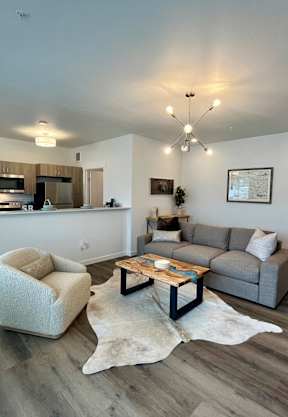 A modern living room with a grey sofa, a white armchair, and a wooden coffee table at Silverbrook Apartments Apartments, Ridgeland, 59901