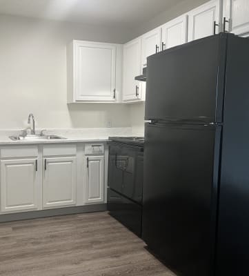 a kitchen with white cabinets and black refrigerator