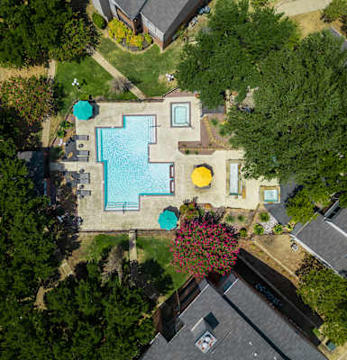 an aerial view of a backyard with a large swimming pool with blue and yellow umbrellas