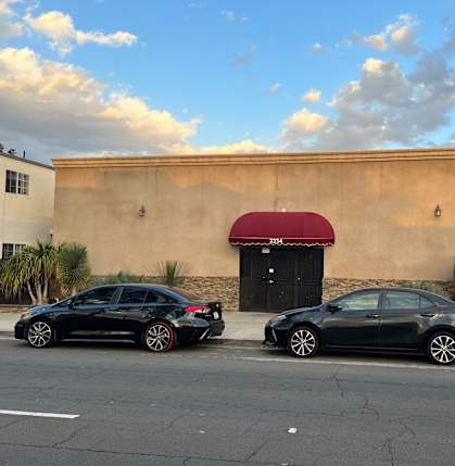 a building with a red awning and two cars parked in front of it