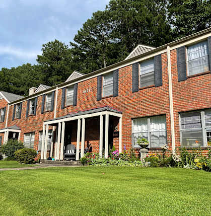 a row of brick apartment buildings with a green yard