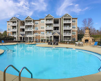 A large swimming pool in front of a multi-story apartment building.