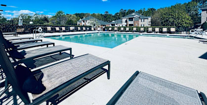 A pool with sun loungers and a building in the background.