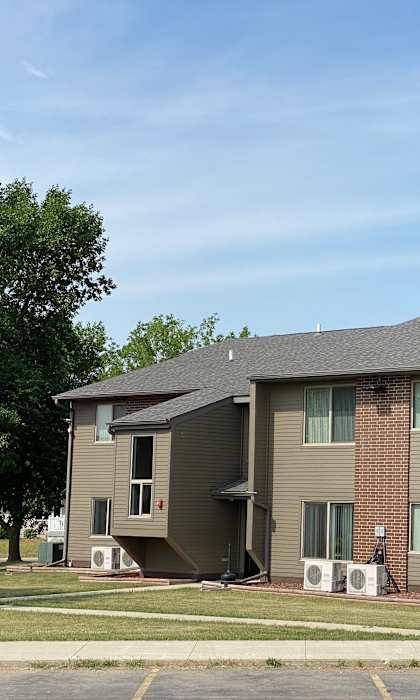 a brown house with a gray roof and some trees