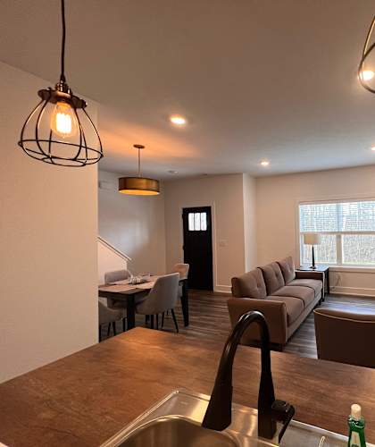 A modern living room with a kitchen area in the foreground. at The Vue at Rivertown Park Townhomes, Wyoming  , MI, 49418