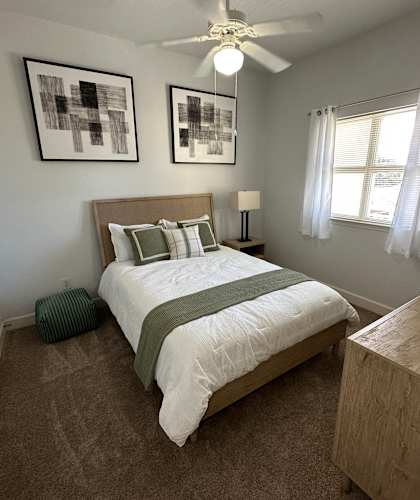 A bedroom with a bed, nightstand, and two pictures on the wall.