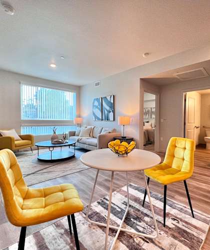 A yellow chair sits in a room with a white table and a rug.