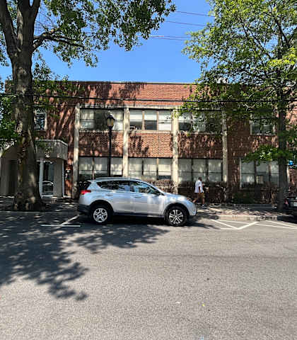 a large brick building with a red roof and a white car parked in front of it