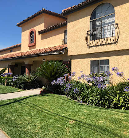 a house with a lawn and flowers in front of it