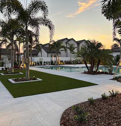 A beautiful outdoor residential area with a swimming pool surrounded by palm trees.
