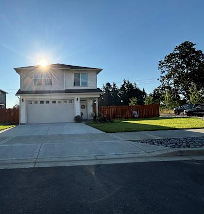 a white house with the sun shining over the driveway