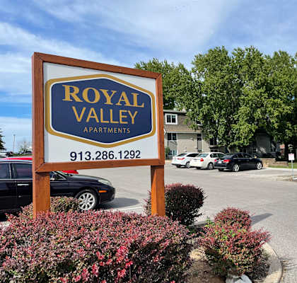 a sign for royal valley apartments in front of a parking lot