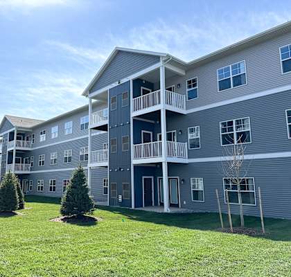 A large apartment complex with multiple balconies and a green lawn in front.